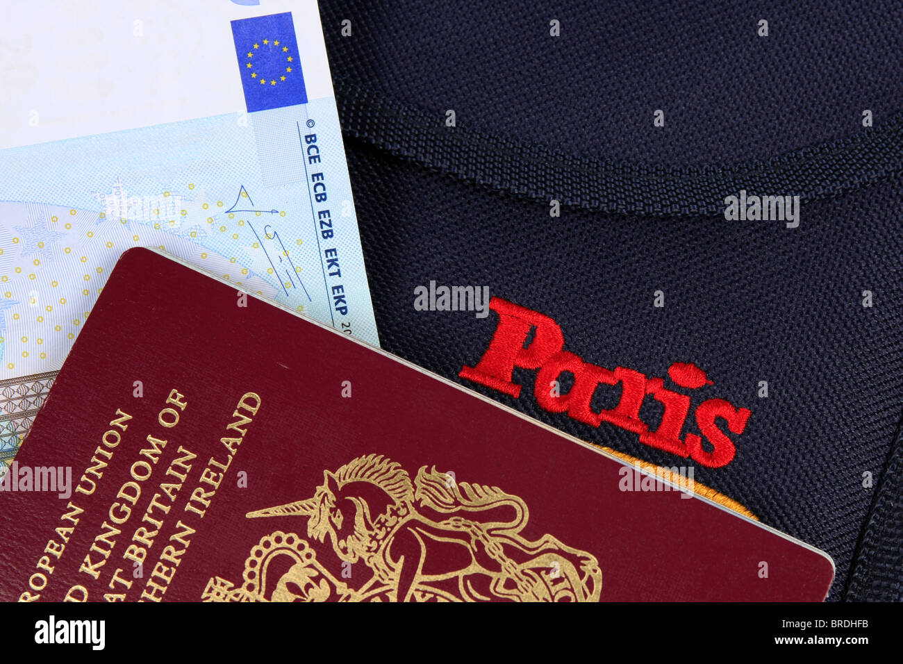 Euro denaro un passaporto britannico e una cartella la promozione di Parigi insieme contro uno sfondo bianco Foto Stock