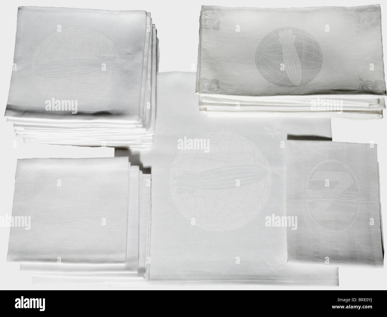 German Zeppelin Shipping Company, un set di tovaglie di seta bianca damask con decorazione della rosa e l'emblema della società nel centro di ogni pezzo nella forma di un airship sopra un globo. Diversi pezzi portano il monogramma 'Sum' del produttore. Il set è composto da un panno da tavolo (105 x 105 cm), cinque guide da tavolo (85 x 45 cm), dieci tovaglioli grandi (60 x 60 cm.) e quattro tovaglioli più piccoli (50 x 50 cm). Anche un tovagliolo di lino con una 'Z' sopra un dirigibile nel centro (58 x 40 cm). Il numero 130 per l'aeronave LZ 130, 'Graf Zeppelin II' è tessuto nei quattro tovaglioli più piccoli. Th, Foto Stock