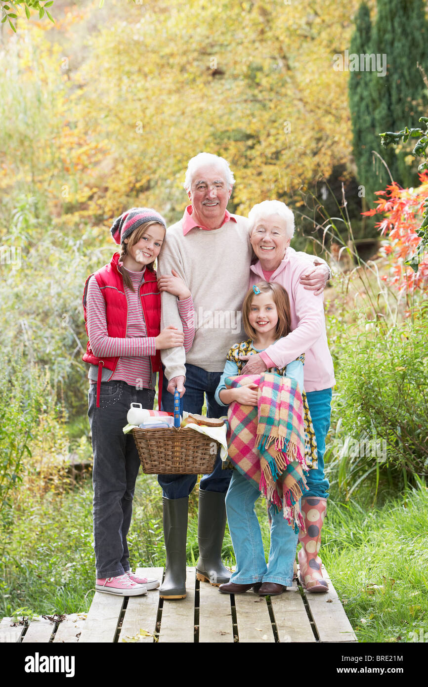 Nonni con i nipoti che trasportano un cestino picnic da Bosco in autunno Foto Stock