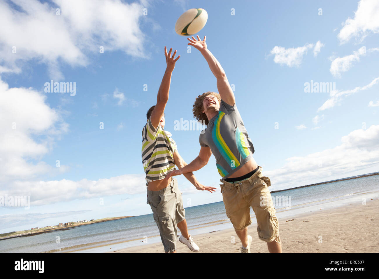 Due ragazzi adolescenti giocando a rugby sulla spiaggia insieme Foto Stock