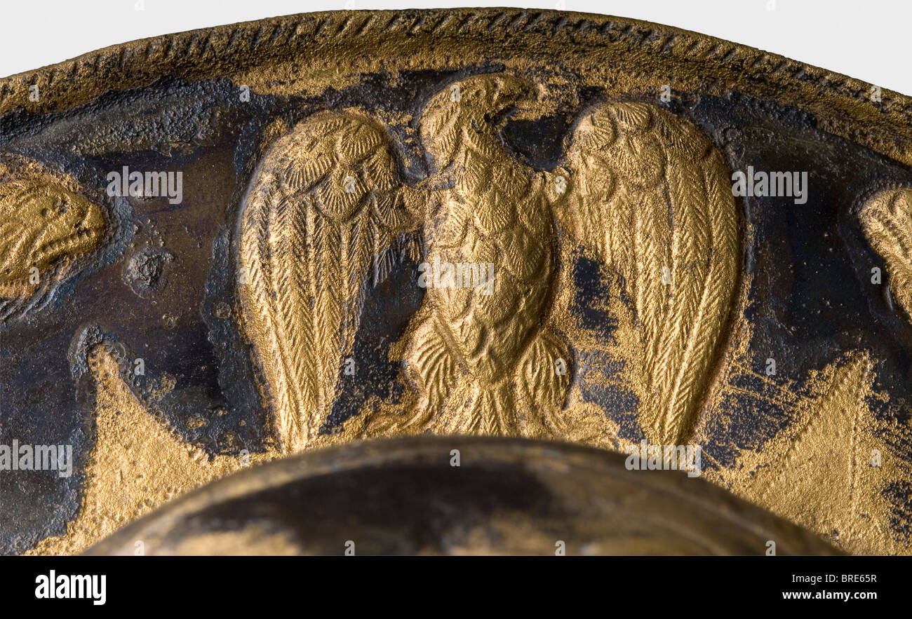 Una parata romana umbo schermo che mostra Minerva, 3rd secolo d.C. Ottone, in scatola in luoghi. Riccamente decorato, insolitamente forma borchia scudo, in precedenza in splendorous contrasto oro-argento. Al centro una rappresentazione della dea Minerva indossando un casco corinzio e seduta su una sedia rivolta a sinistra. Riccamente cesellato con motivi tipici per armatura cerimoniale, e figure decorative aggiuntive esposte sul bordo dell'umbo, in particolare un'aquila imperiale romana con ali allargate sopra la figura centrale della dea. L'accessorio (non presente) sul retro, , Foto Stock