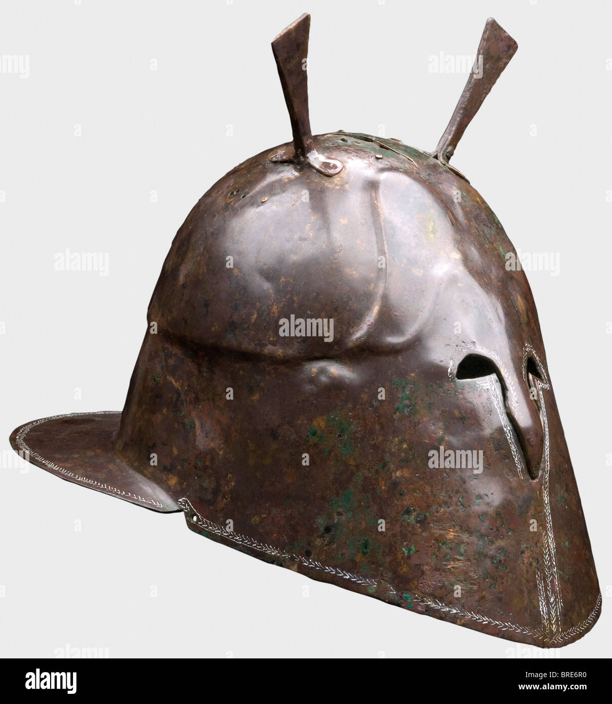 Un casco apuliano-corinzio, Un Casco 6th/5th secolo a.C. con cranio alto e pseudo-cheekpieces chiusi completi, con le piccole aperture degli occhi e la breve protezione sporgente del naso che formano le uniche aperture davanti. Sopracciglia e sopracciglia contornate, fessure laterali corte e una protezione del collo molto ampia e flangiata. Circondato da un fine motivo a base di pesce (reso visibile con inchiostro bianco), e con un ornamento ad albero sopra la fessura sul lato sinistro. Due supporti in lamiera trapezoidale rivettata e fori per rivetti aggiuntivi sulla calotta si attestano ad altre decorazioni del casco e r, Foto Stock