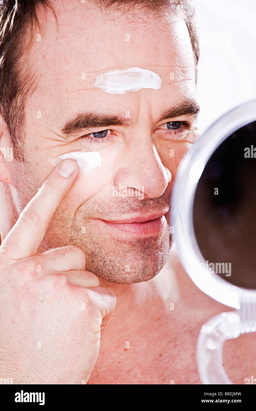 Uomo sorridente mettendo su una lozione Foto Stock