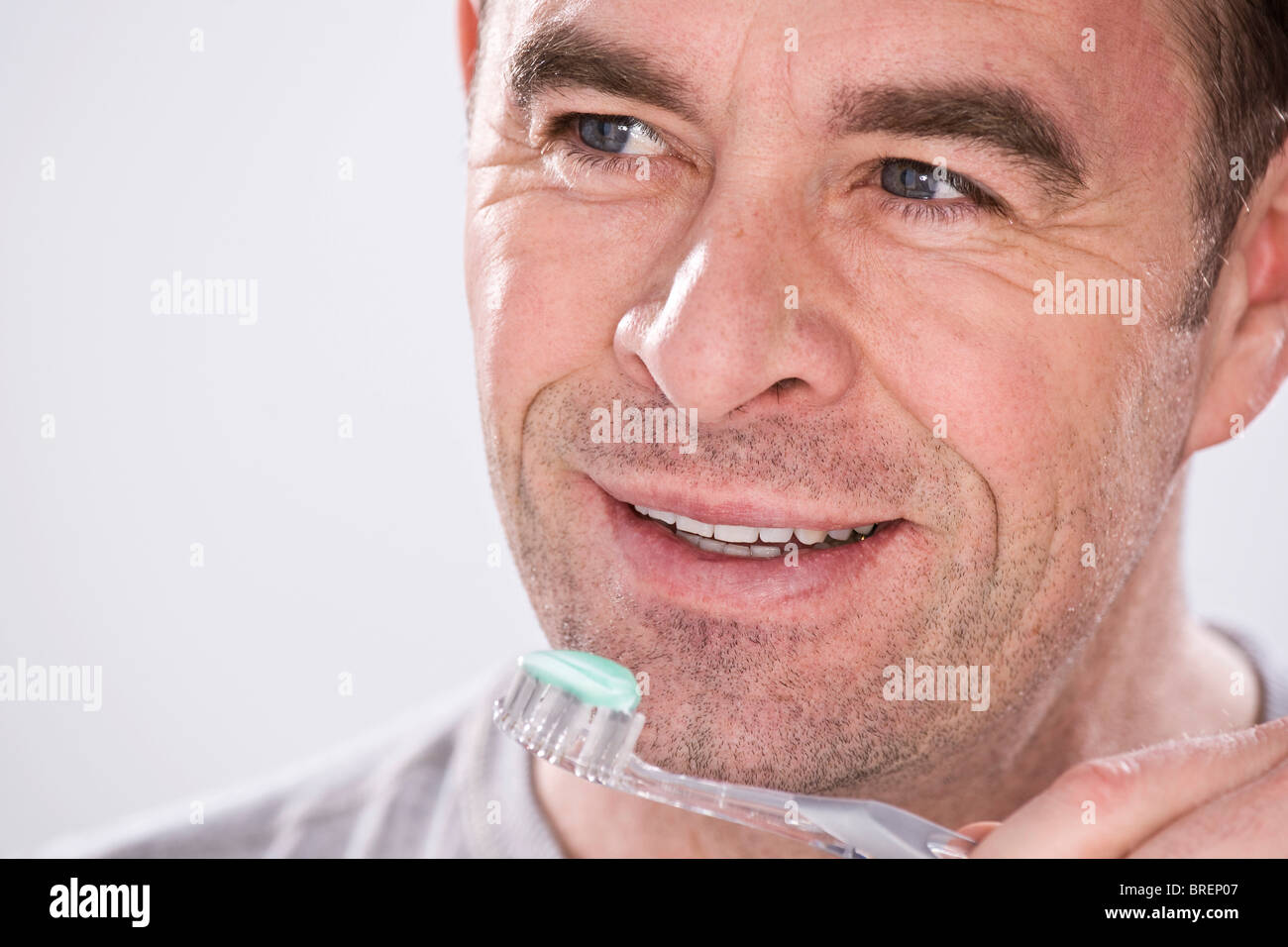 Uomo sorridente tenendo uno spazzolino da denti Foto Stock