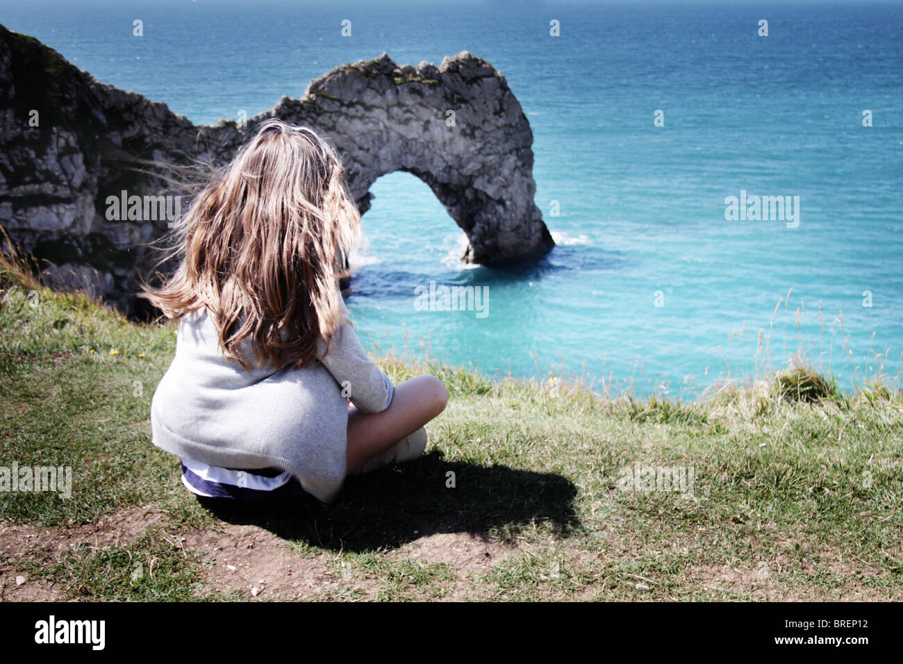Ragazza sedeva dalla porta di Durdle,Dorset,l'Inghilterra,UK Foto Stock