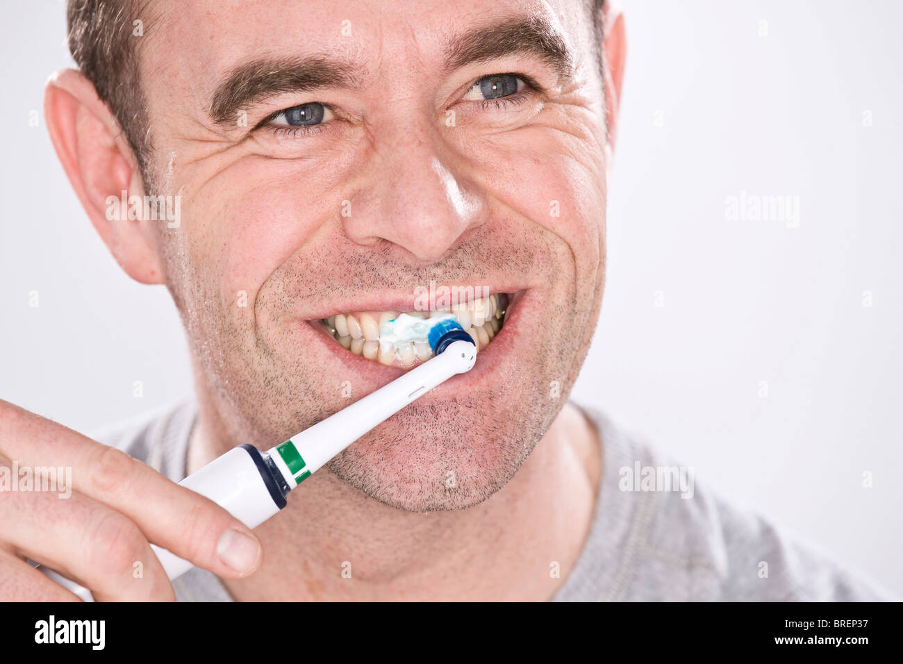 Uomo che pulisce i denti con uno spazzolino da denti elettrico Foto Stock