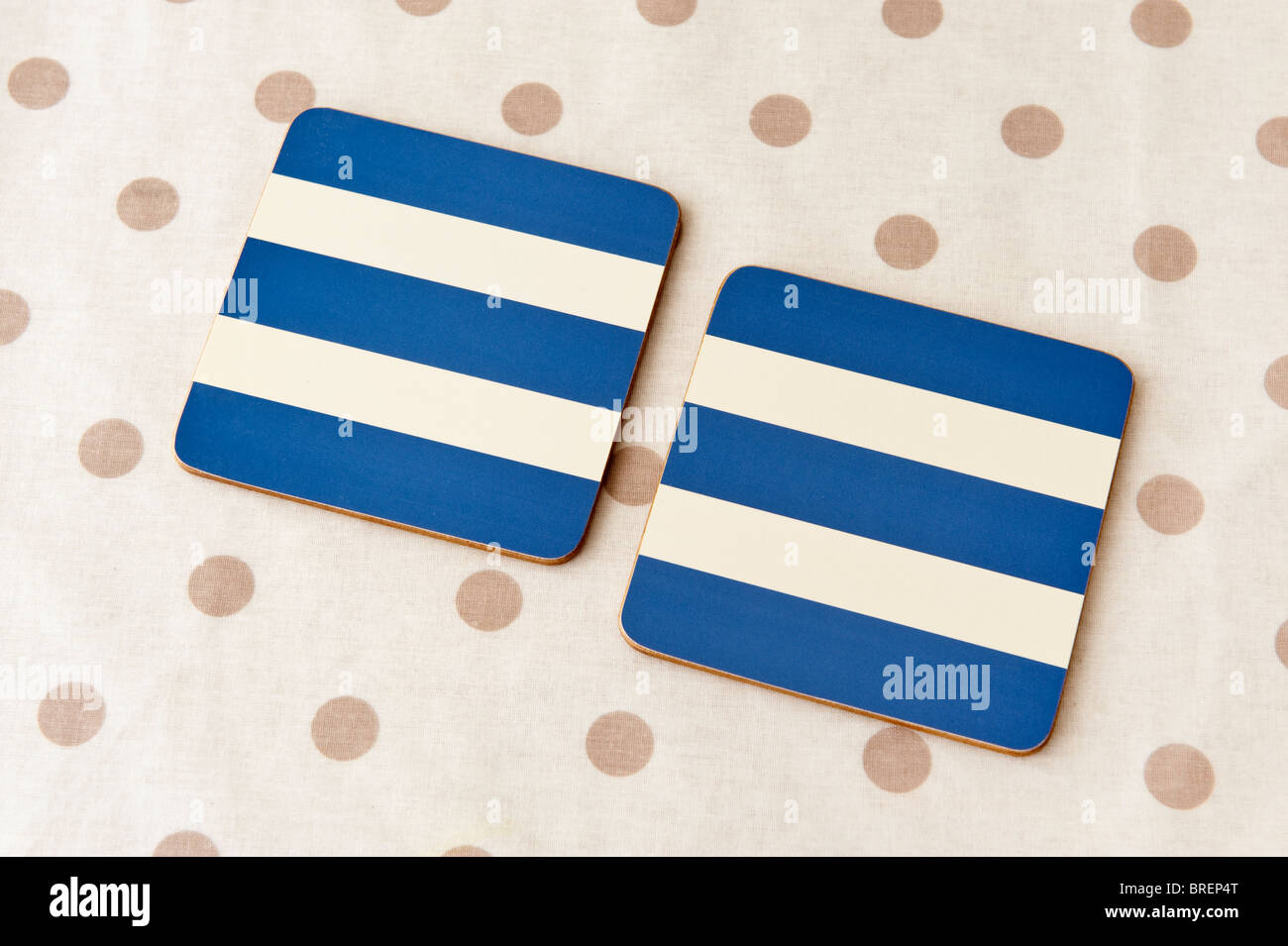 Due blu e crema striped coaster sottopiatti su un color crema e marrone e maculato tovaglia in plastica Foto Stock