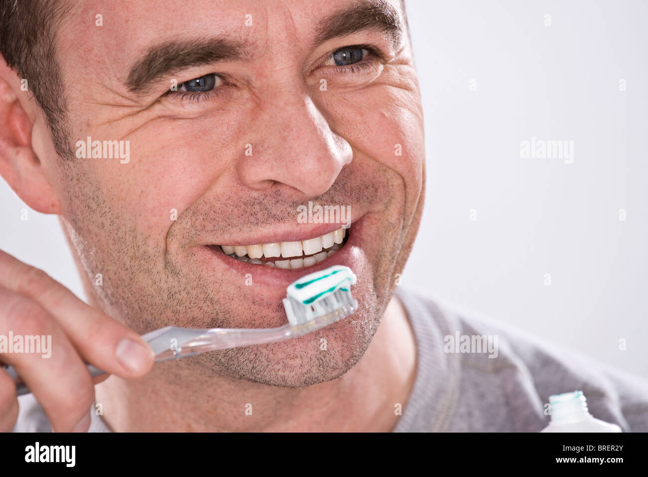 Uomo sorridente tenendo uno spazzolino da denti Foto Stock