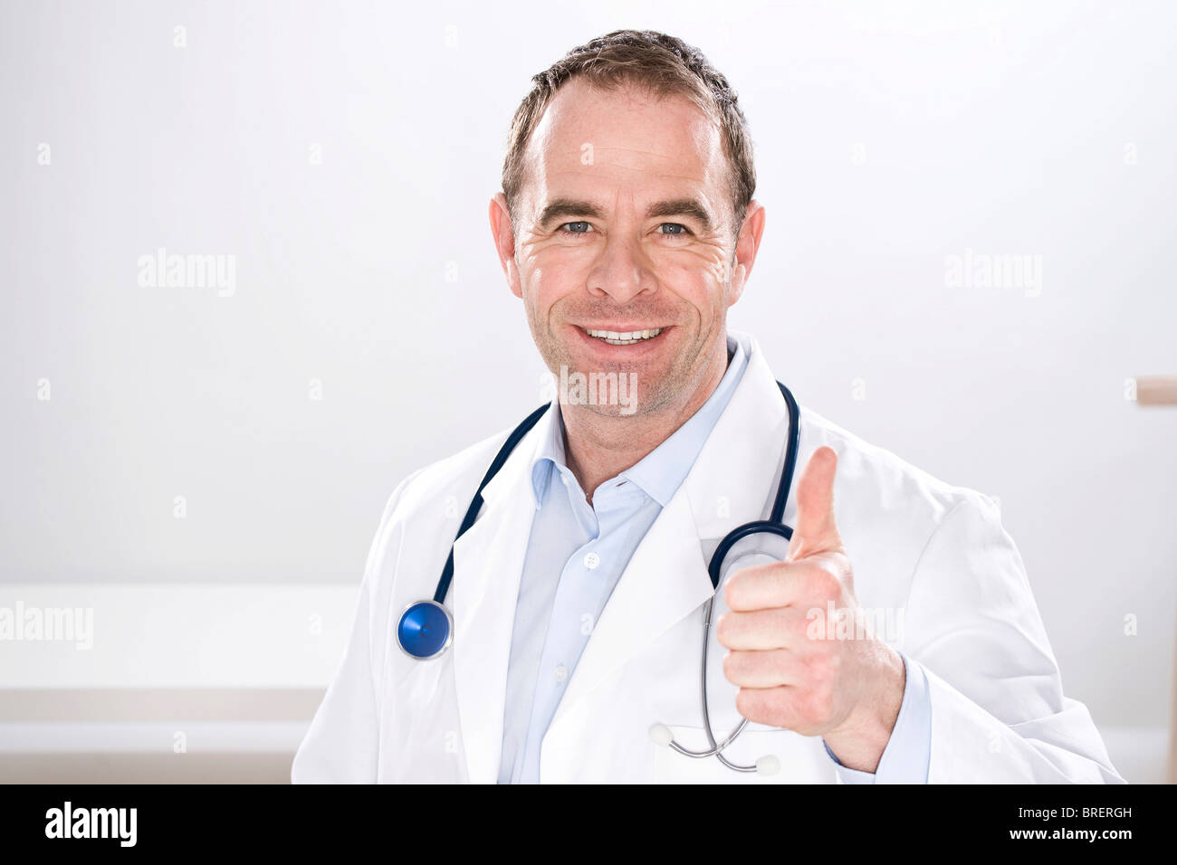 Uomo sorridente indossando medical scrubs, con uno stetoscopio, pollice in su Foto Stock