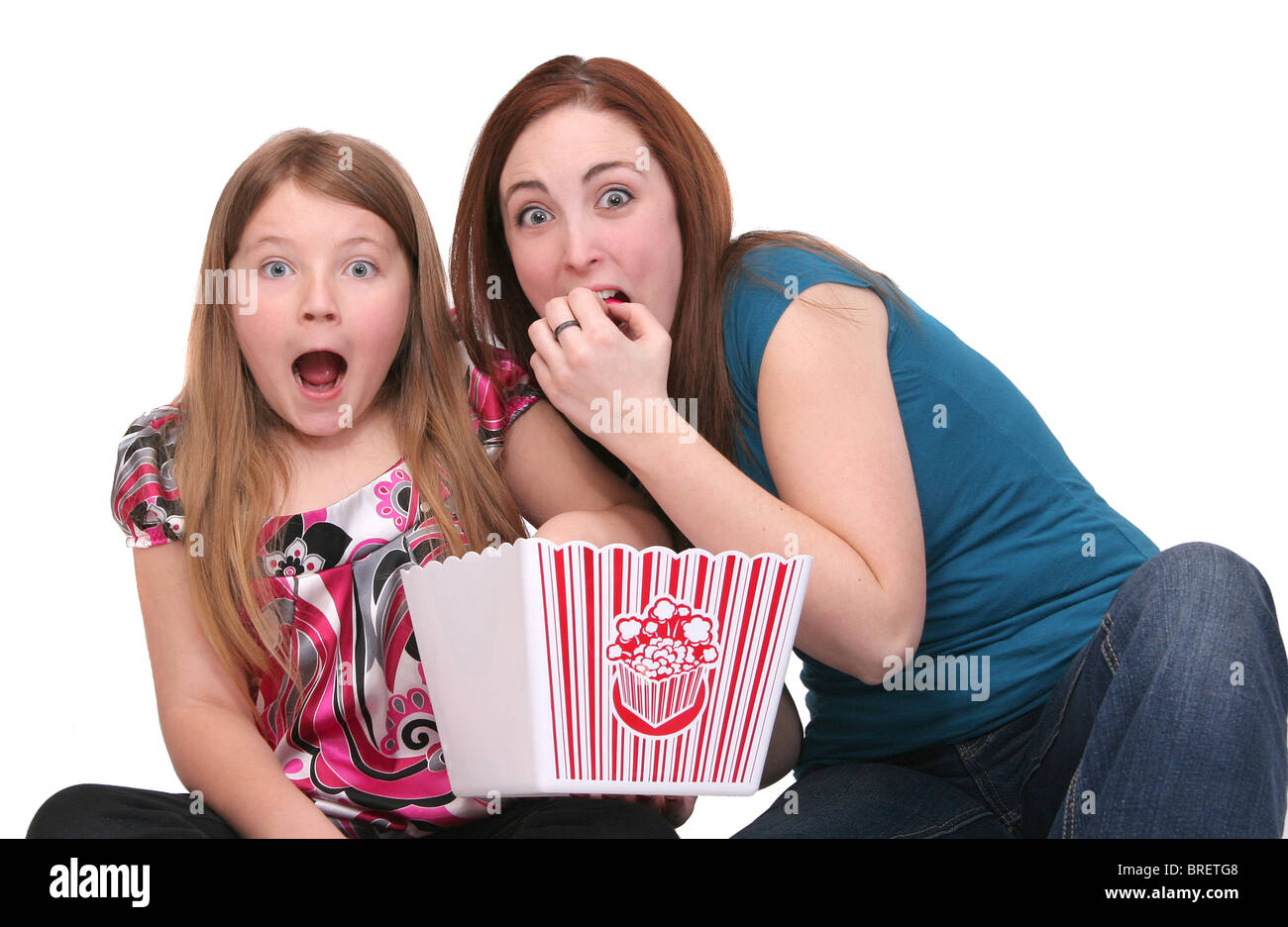 Due sorelle un bambino e teen la visione di un filmato con popcorn su bianco Foto Stock