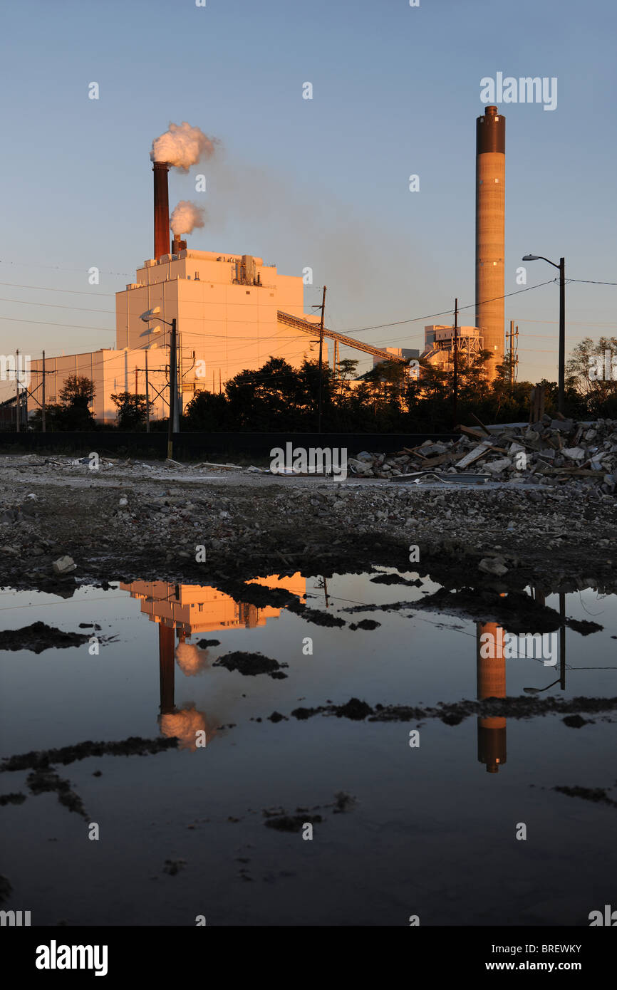 Sito industriale con fumaioli di macerie e acqua riflessioni in primo piano Foto Stock