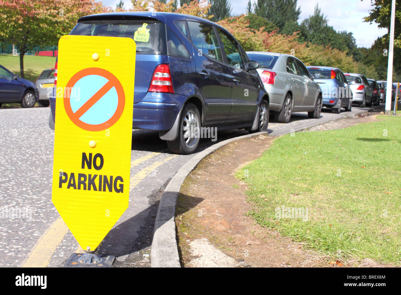 Fila di automobili parcheggiate illegalmente sulle doppie linee gialle Foto Stock