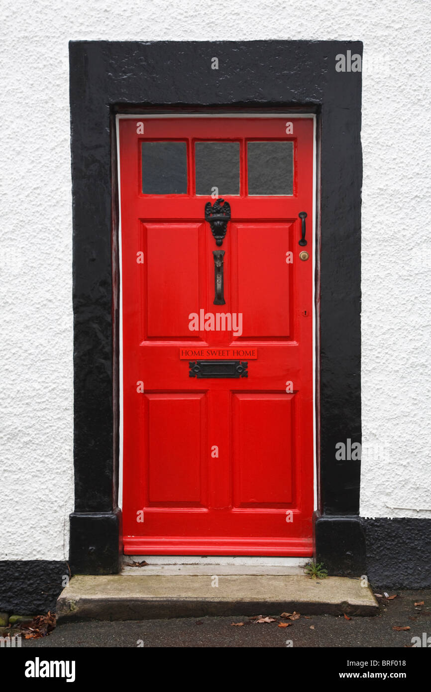 La porta anteriore di una tradizionale casa britannica dipinto di rosso brillante e con una casa dolce casa segno Foto Stock