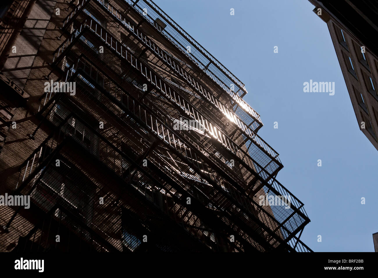 Iron Fire Escape glinting in sun. Un acciaio multipiano fire escape zig-zag lungo il lato di una vecchia Boston alto edificio. Foto Stock