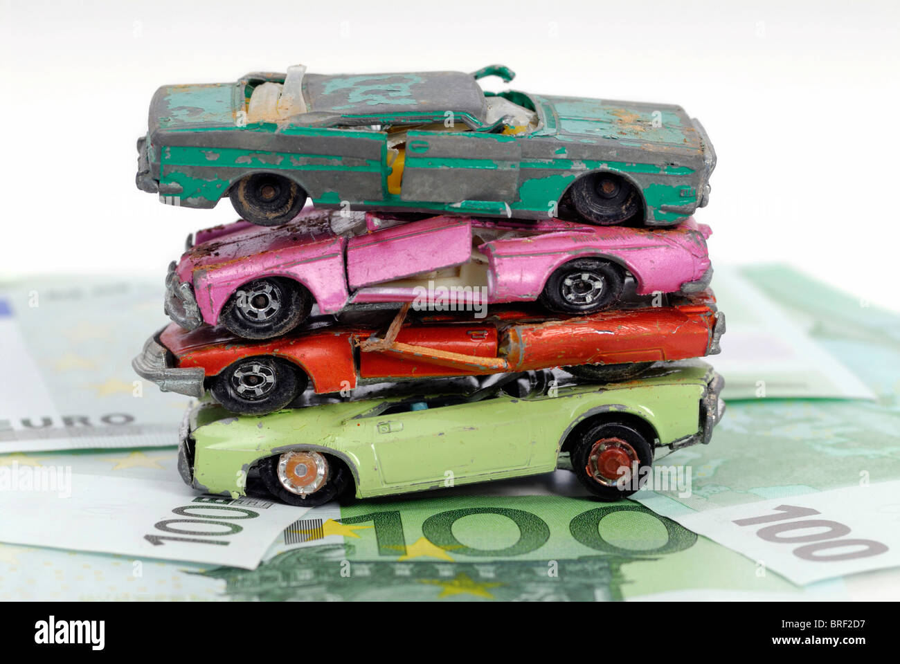 Rotto auto in miniatura su banconote, immagine simbolica per il premio di demolizione Foto Stock