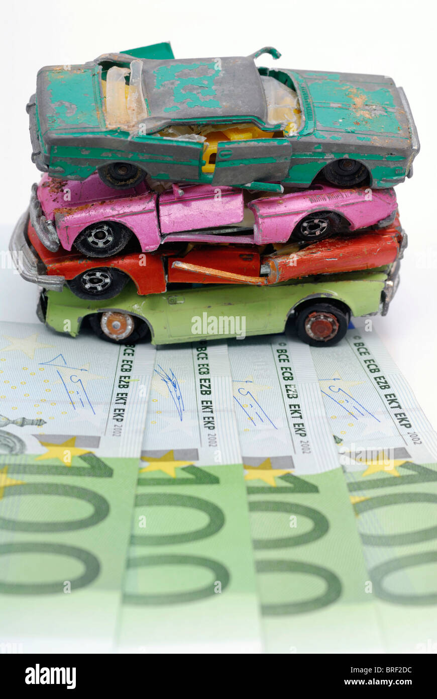 Rotto auto in miniatura su banconote, immagine simbolica per il premio di demolizione Foto Stock