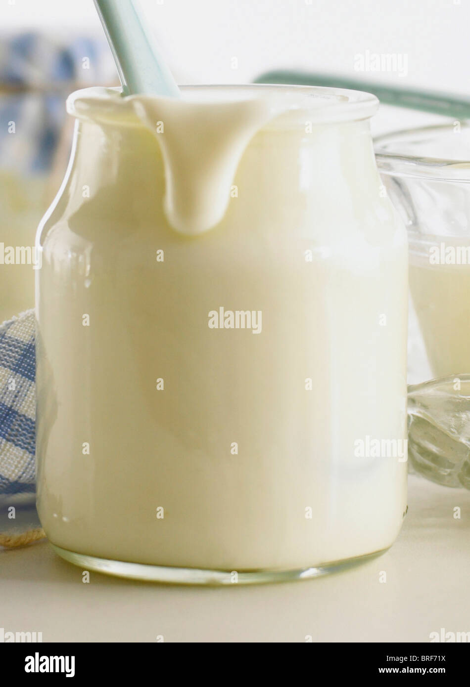 Yogurt naturale in un vaso di vetro con un gocciolamento proveniente di lato verso il basso Foto Stock