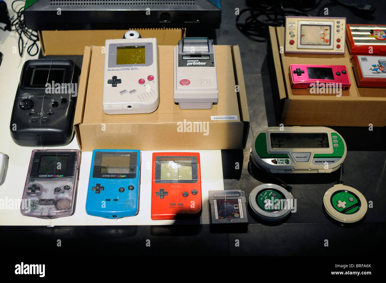 Diversi dispositivi video portatili console di gioco sullo schermo durante una mostra di video giochi; incluso il famoso Nintendo Game Boy. Foto Stock