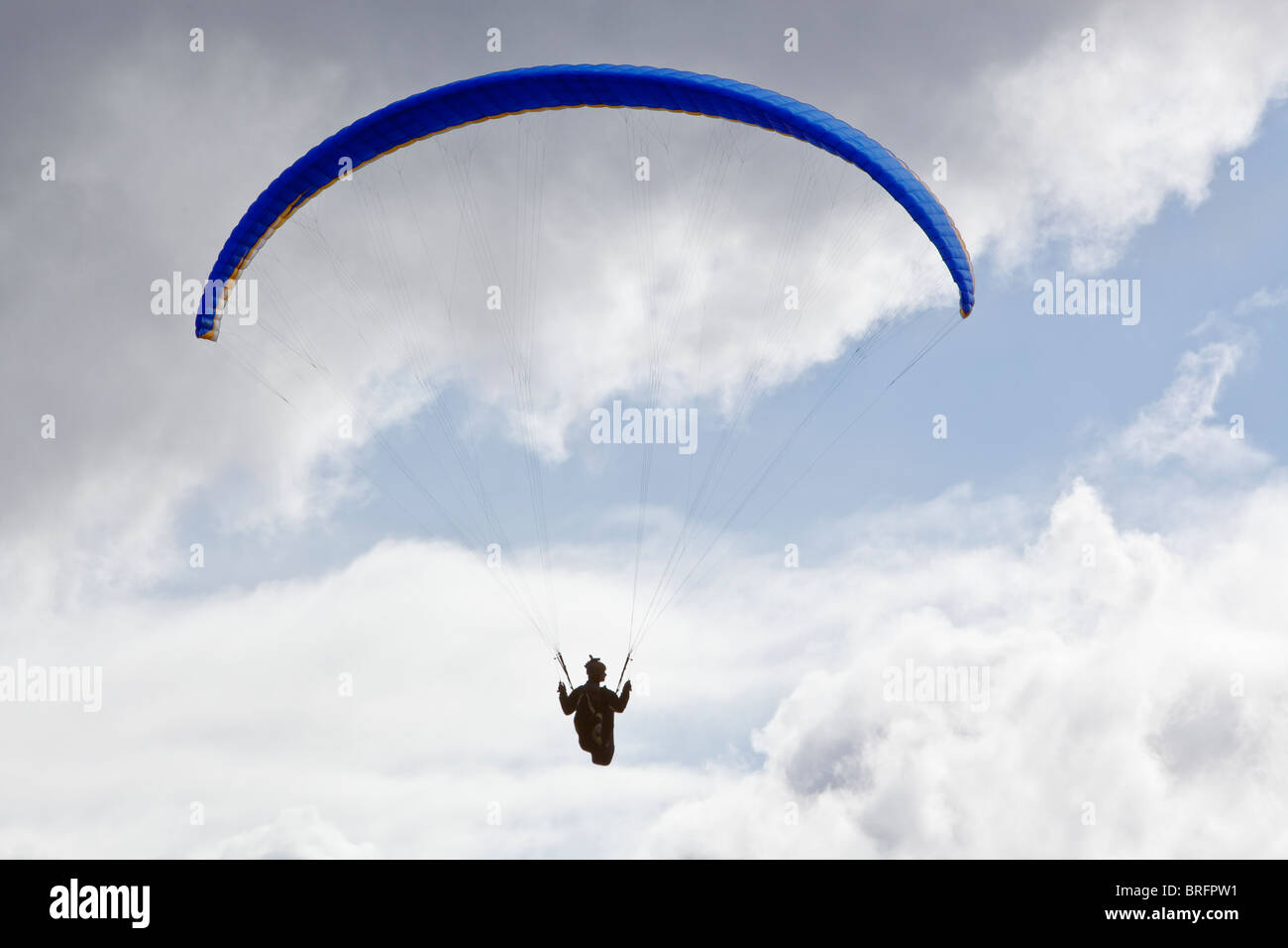 Una persona è sospeso da un paracadute-simili di parapendio e galleggia nell'aria in Galles del Sud. Foto Stock
