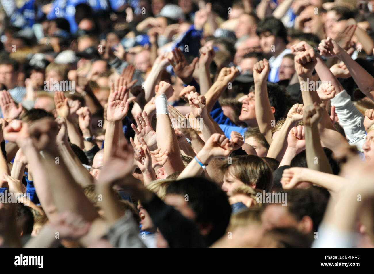 Gli spettatori della partita di calcio alza le mani in aria a sostegno del loro team Foto Stock