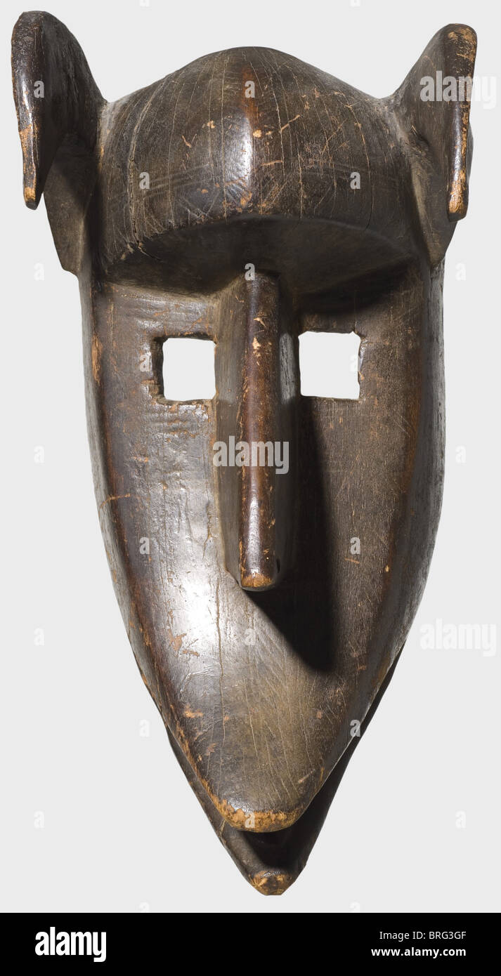 Una maschera di bambana ntomo, Burkina Faso, prima metà del XX secolo. Maschera di legno con patina scura, fronte fortemente sporgente, semplici aperture quadrate per gli occhi, e un naso forato a forma di cuneo. Le orecchie grandi si piegano in avanti, e c'è una lingua indicata nella bocca larga, aperta. Segni di età e di utilizzo. Resti di decorazioni geometriche. Un po' ammaccato, la rottura di ritiro sulla destra. Altezza 40 cm. Storico,storico,belle arti,arte,tribù,tribù,tribale,Africano,Africa,etnico,etnico,etnico,esotico,wodden,scultura,sculture,fico,diritti aggiuntivi-clearences-non disponibile Foto Stock