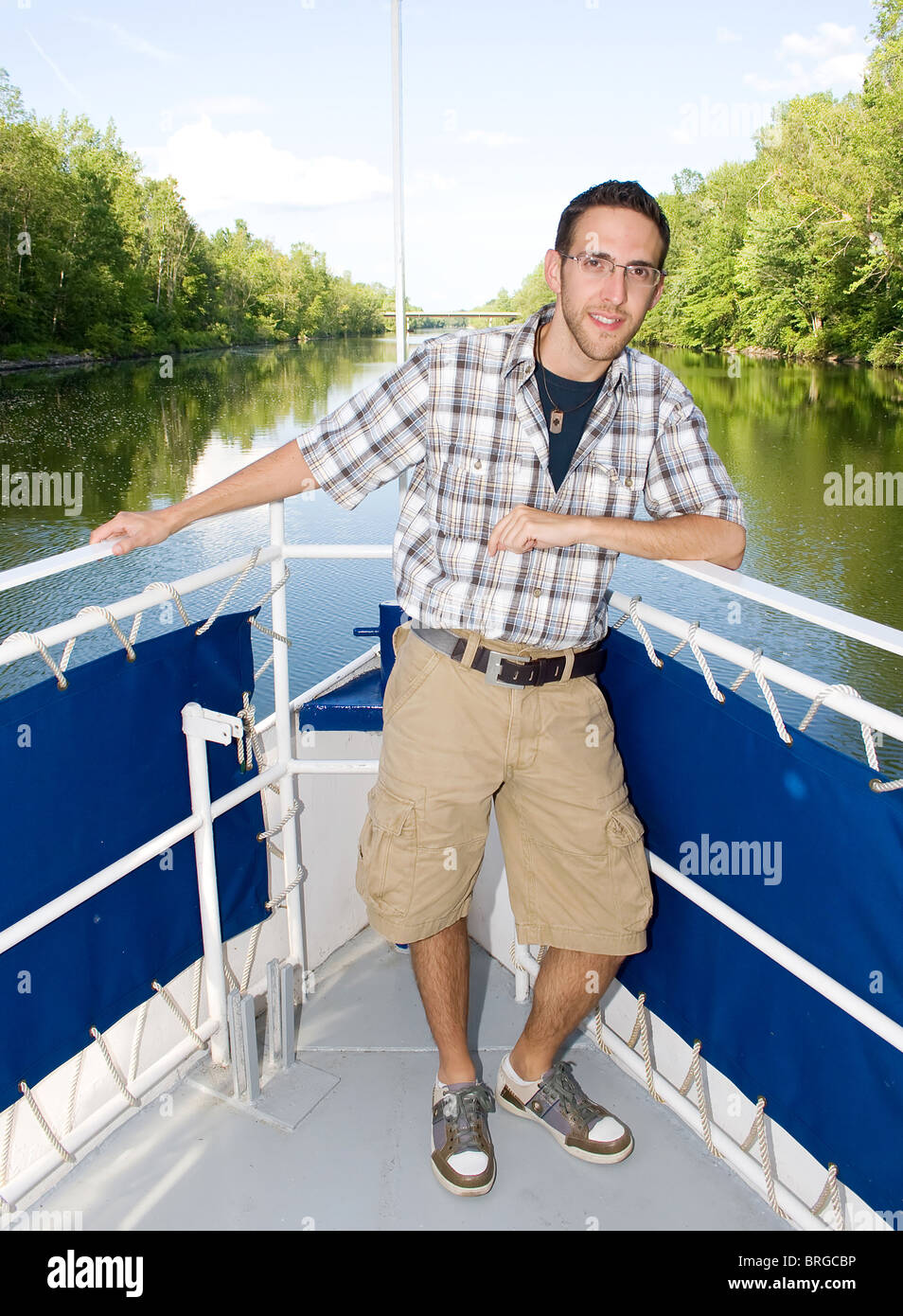 Un giovane maschio adulto con gli occhiali sulla parte anteriore di una imbarcazione dando un tour nel corso di un viaggio sul fiume Foto Stock