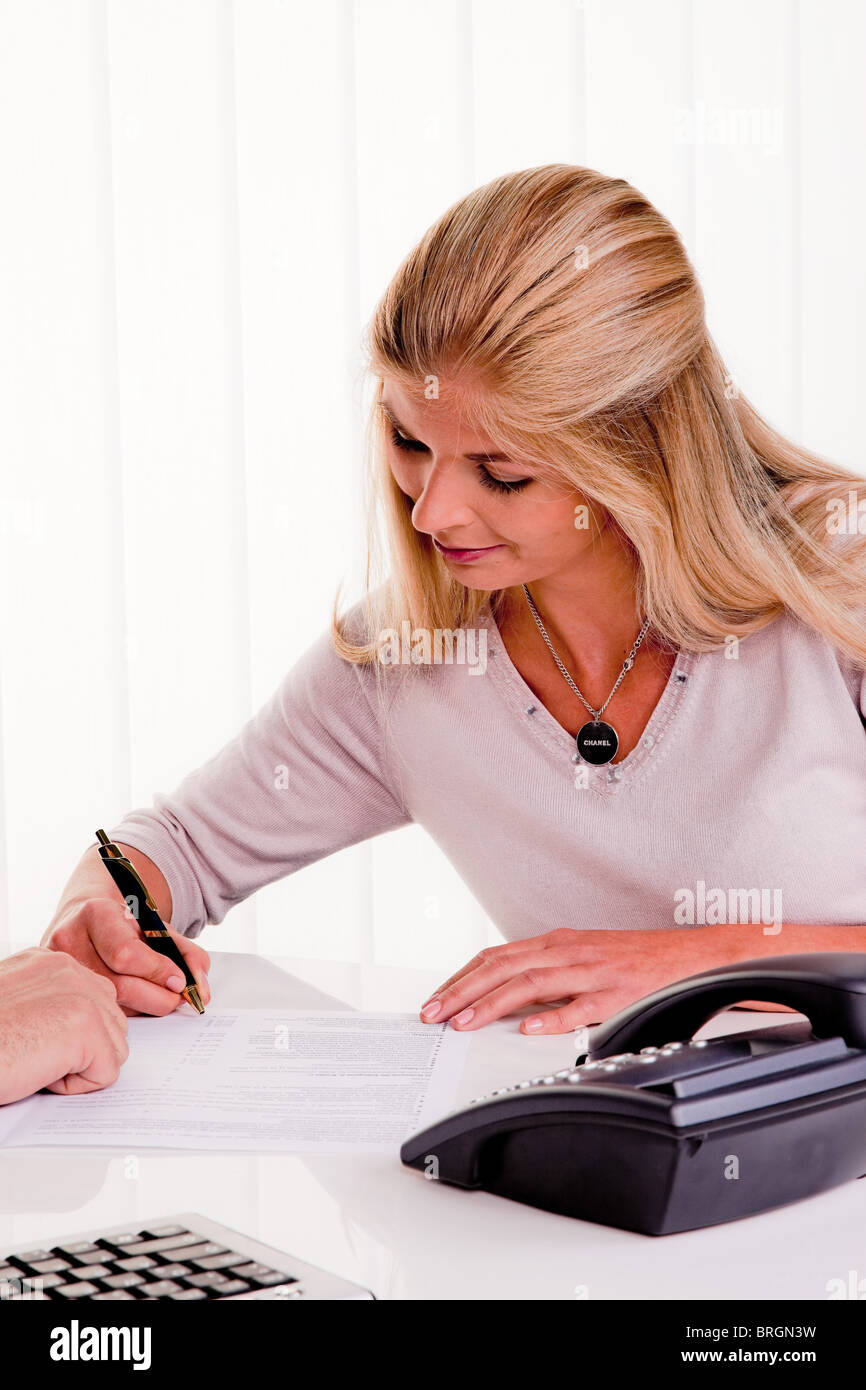Giovane donna firma un contratto in un ufficio Foto Stock