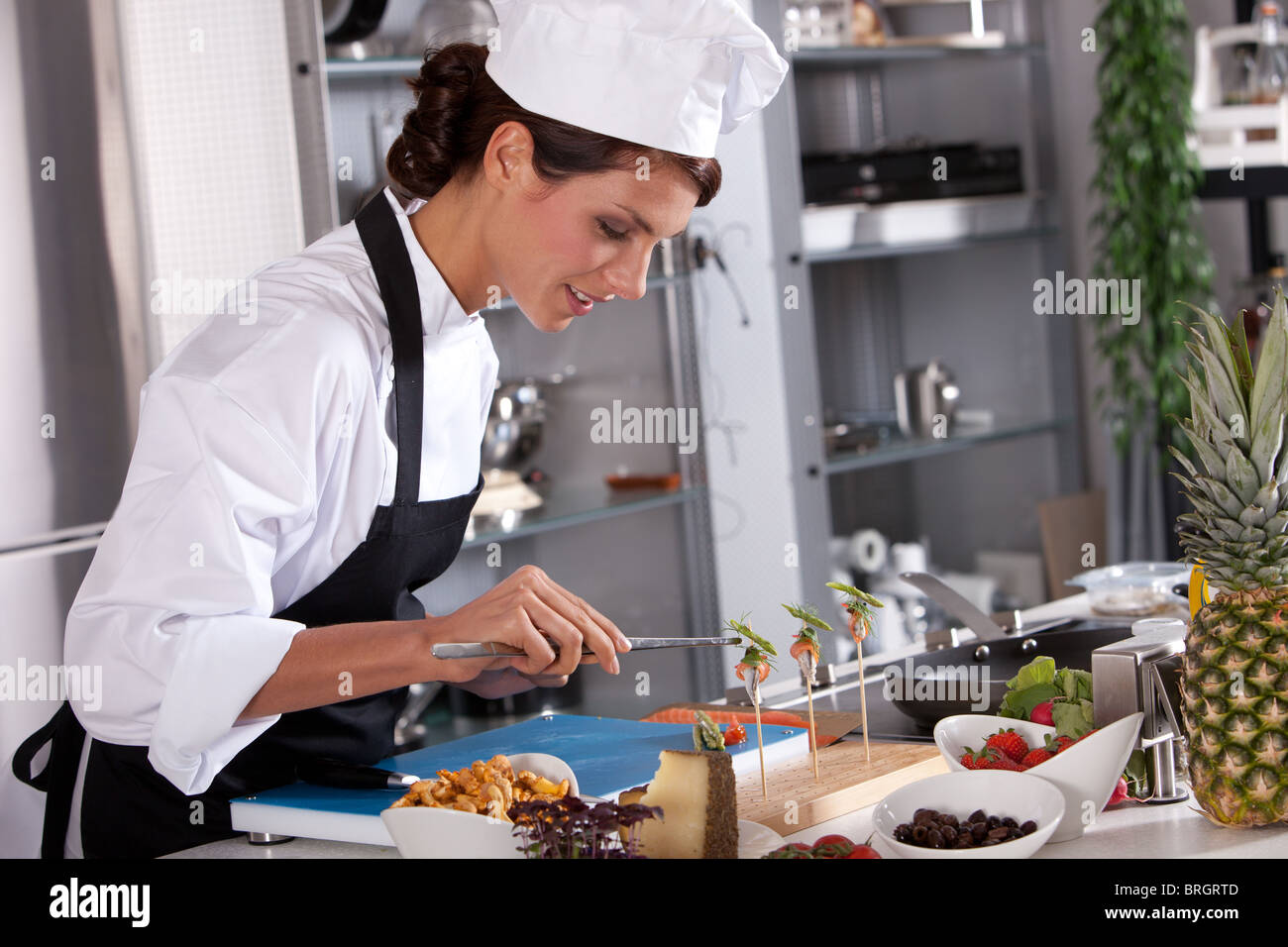 Bella chef prepara un divertire con pinze Foto Stock