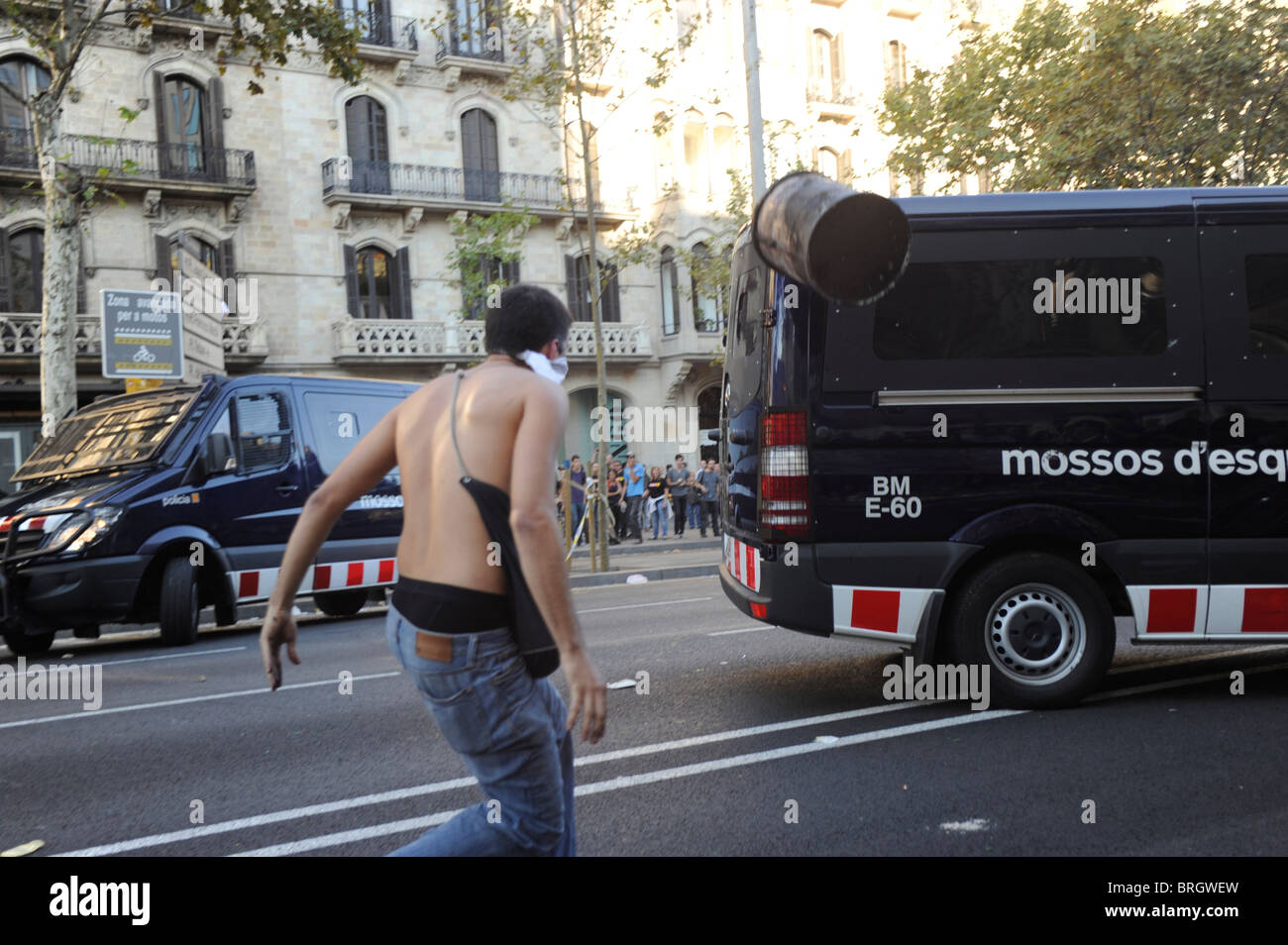 Un attivista anti sistema genera un cestino della spazzatura contro un furgone della polizia durante scontri al centro della città di Barcellona durante lo sciopero. Foto Stock