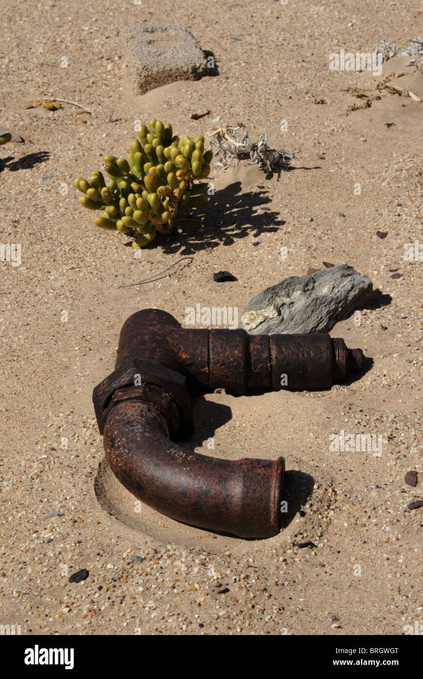 Decadendo pezzo di tubo giacente nella sabbia del deserto namibiano nel diamante abbandonata città di scavo Kolmanskop. Foto Stock