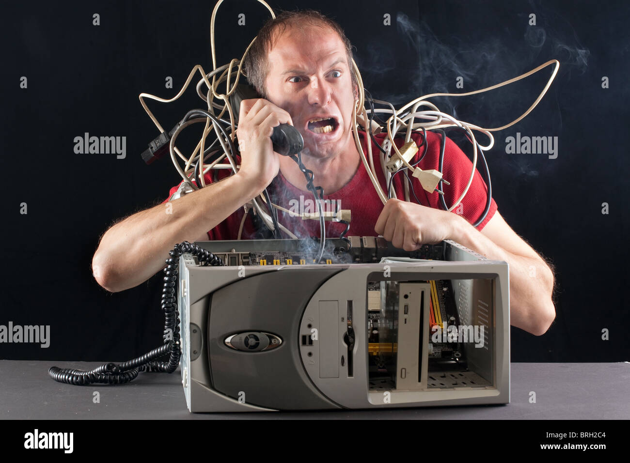 L'uomo con il suo computer la masterizzazione di telefonare con il servizio di assistenza tecnica Foto Stock