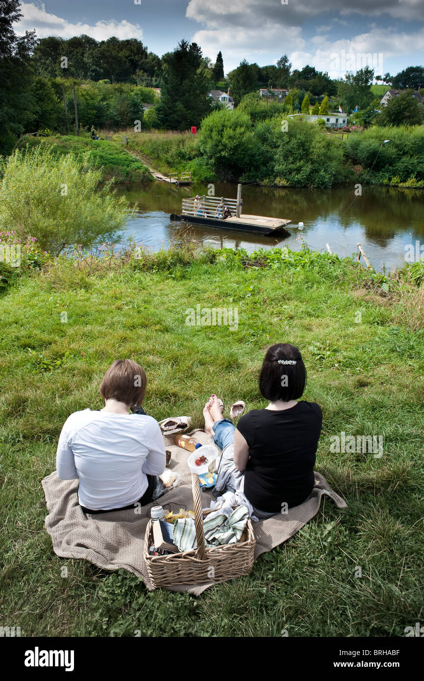 Due persone hanno un picnic guardando Hampton Loade traghetto attraversa il fiume Severn vicino a Bridgnorth, Shropshire, Regno Unito Foto Stock