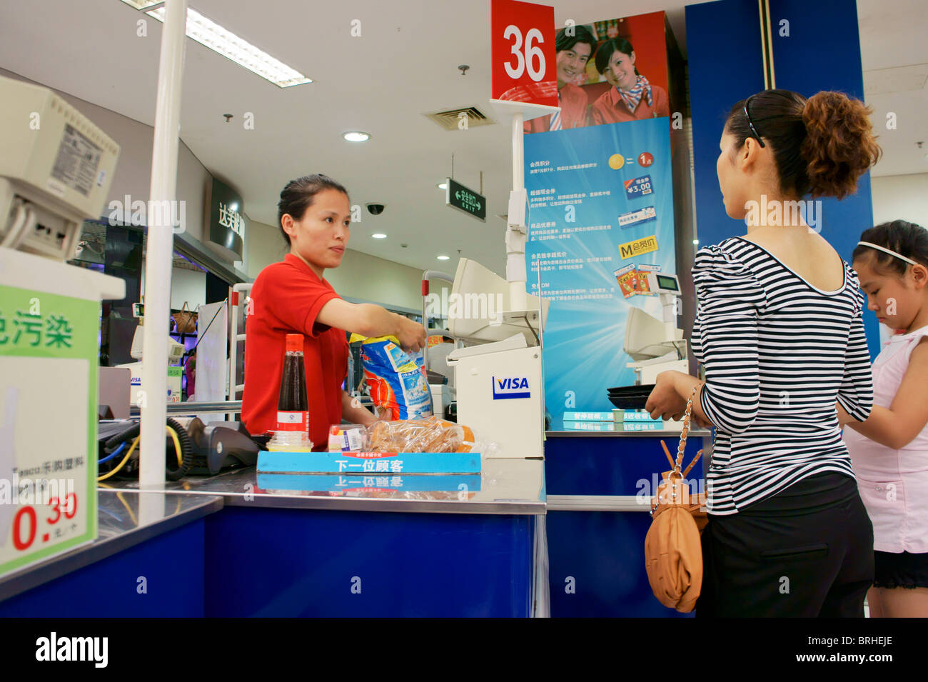 Songjiang, Shanghai, Cina. Madre cinese e la figlia gli acquirenti in coda alla cassa pagare fino a del supermercato Tesco Foto Stock