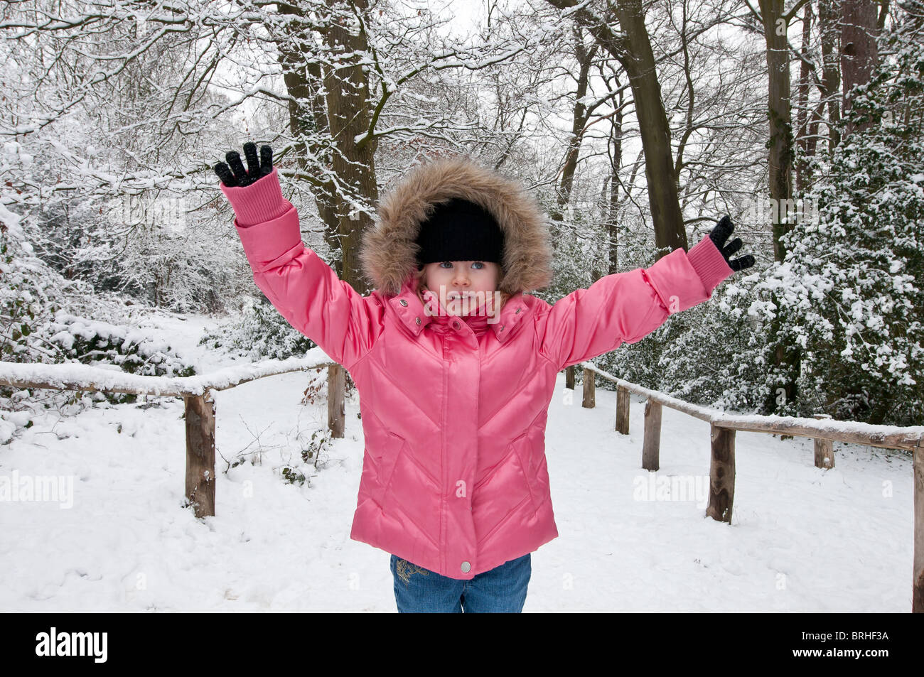 Ragazza quattro bambino giovane femmina camicia rosa giocare giocare divertimento guanti hat sorriso freddo, neve invernale, Kent, England, Regno Unito Foto Stock