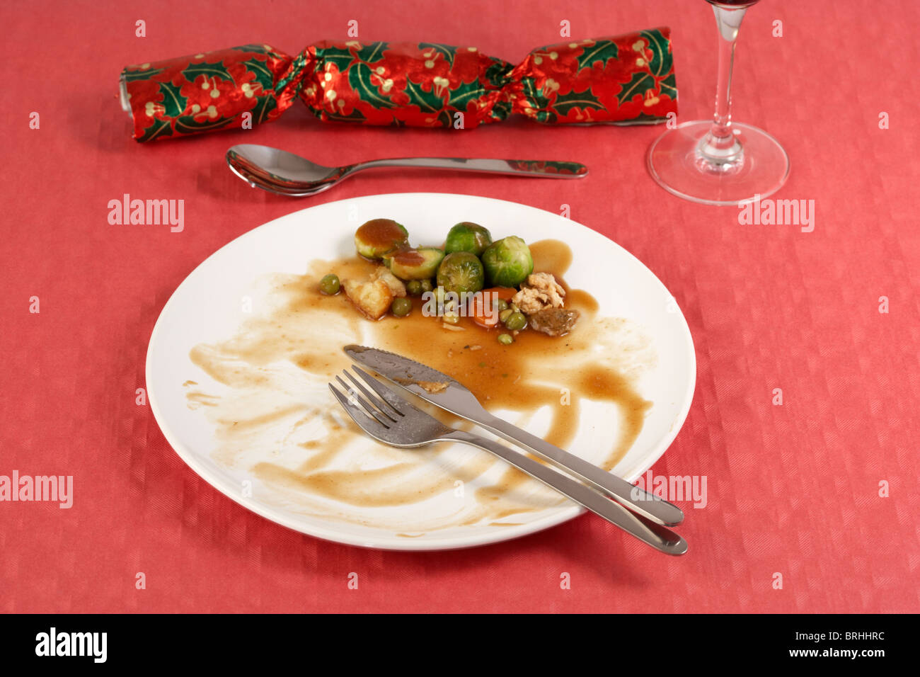 Terminata la cena di Natale con i germogli a sinistra su White dinner piastra sulla tovaglia rosso Christmas Cracker Foto Stock