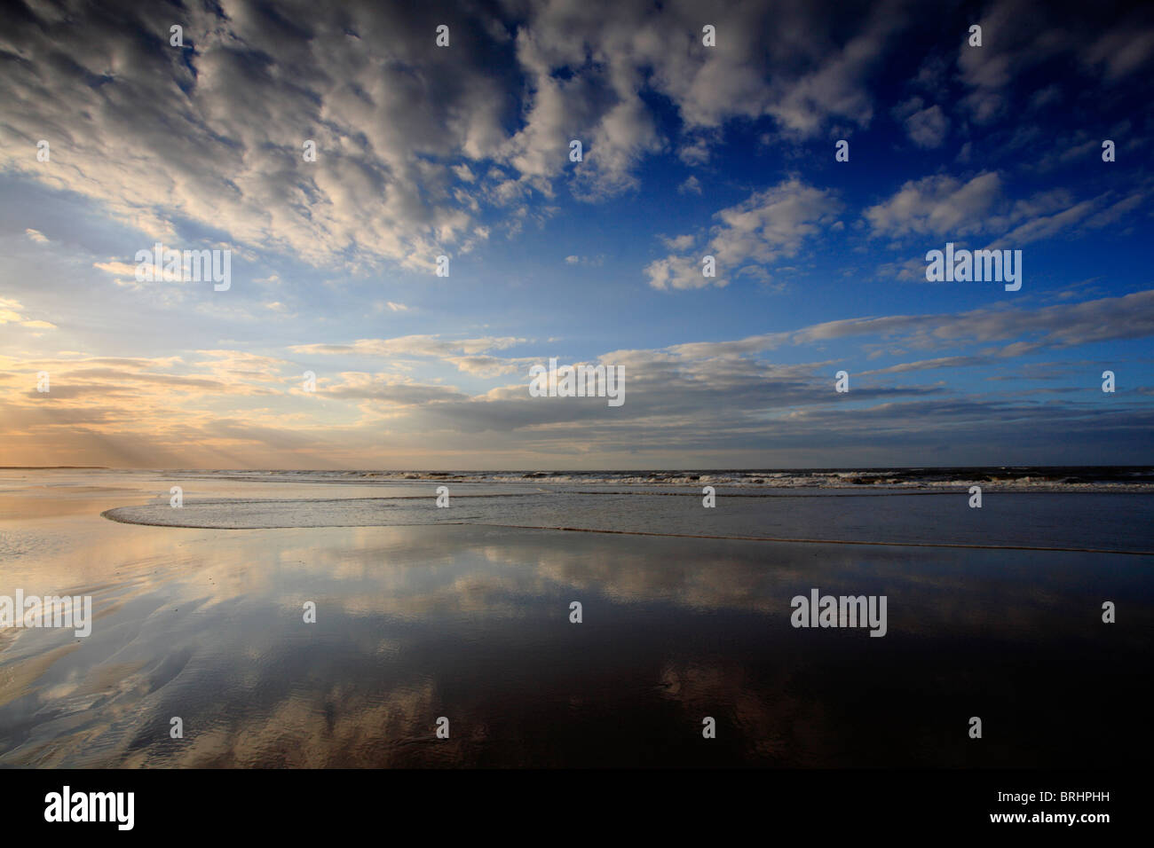 Sky riflessa nella sabbia bagnata a Brancaster Beach a nord Norfok costa. Foto Stock