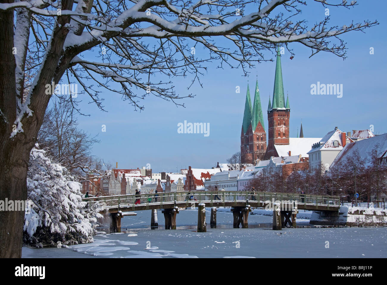 Le chiese di San Petri e Santa Maria che sovrasta le case storiche lungo il fiume congelato trave, Lubecca in inverno, Germania Foto Stock