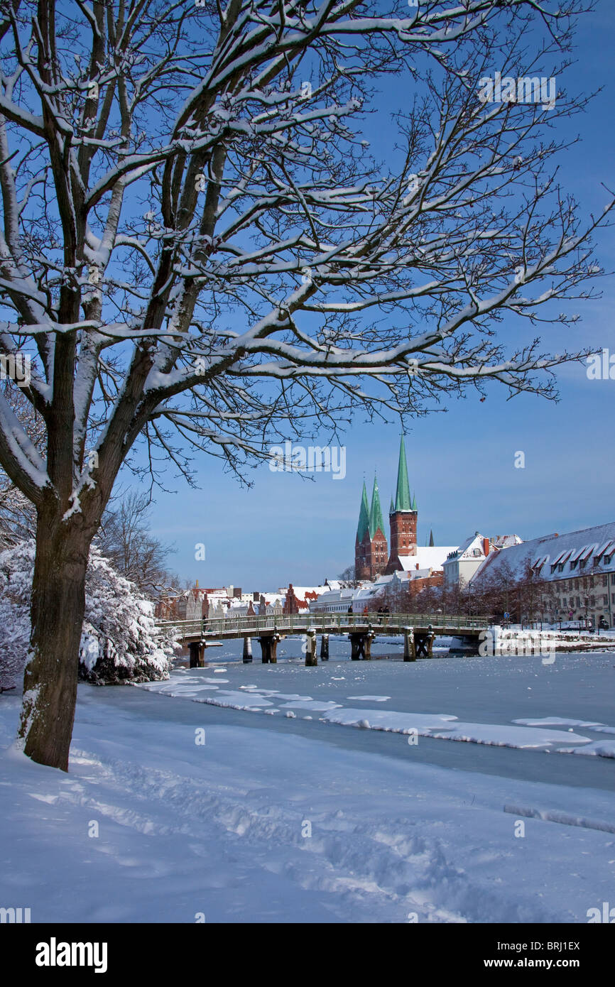 Le chiese di San Petri e Santa Maria che sovrasta le case storiche lungo il fiume congelato trave, Lubecca in inverno, Germania Foto Stock