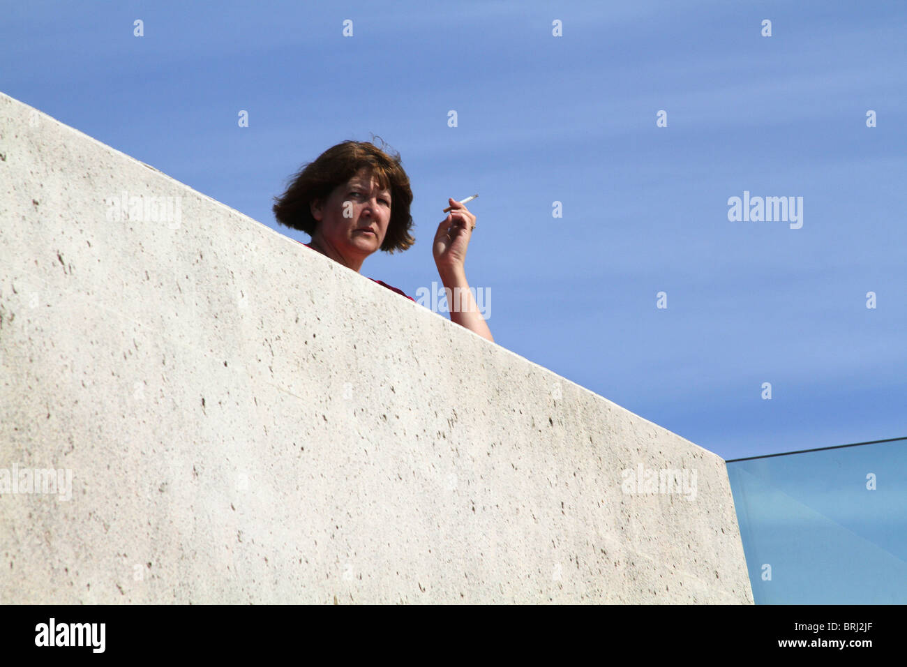 Donna con la sigaretta nella luce del sole. Foto Stock