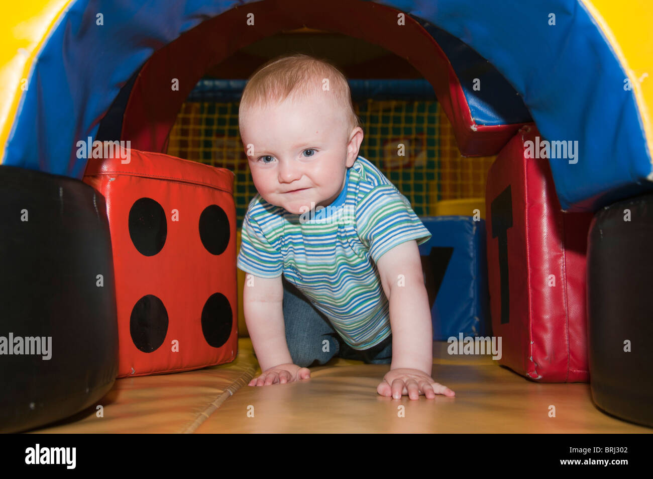 1 anno di età bambino gattona attraverso un tunnel di riproduzione Foto Stock