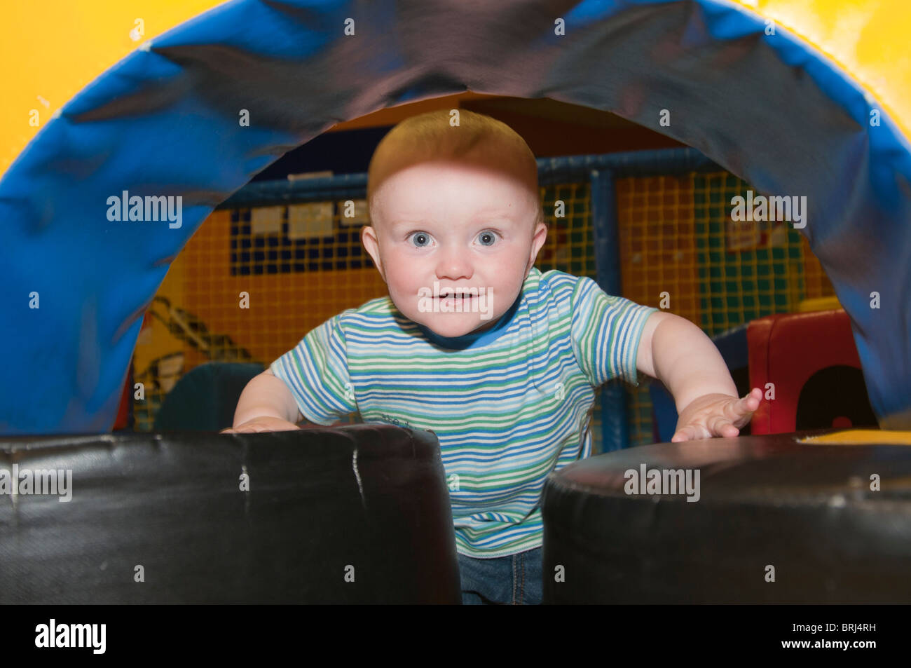 1 anno di età bambino gattona attraverso un tunnel di riproduzione Foto Stock