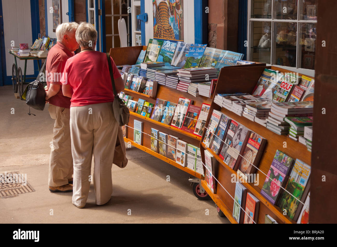 Una coppia in cerca di libri nella Carriage House Gift shop store a Muncaster Castle attrazione turistica in Cumbria , Inghilterra , Regno Unito Foto Stock