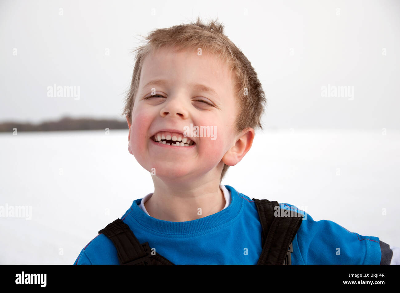 Un sorridenti giovane ragazzo in inverno la neve. Foto Stock