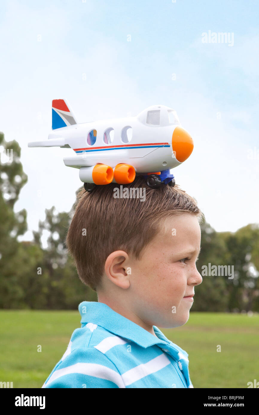 Ragazzo con aeroplano di plastica sulla sua testa Foto Stock