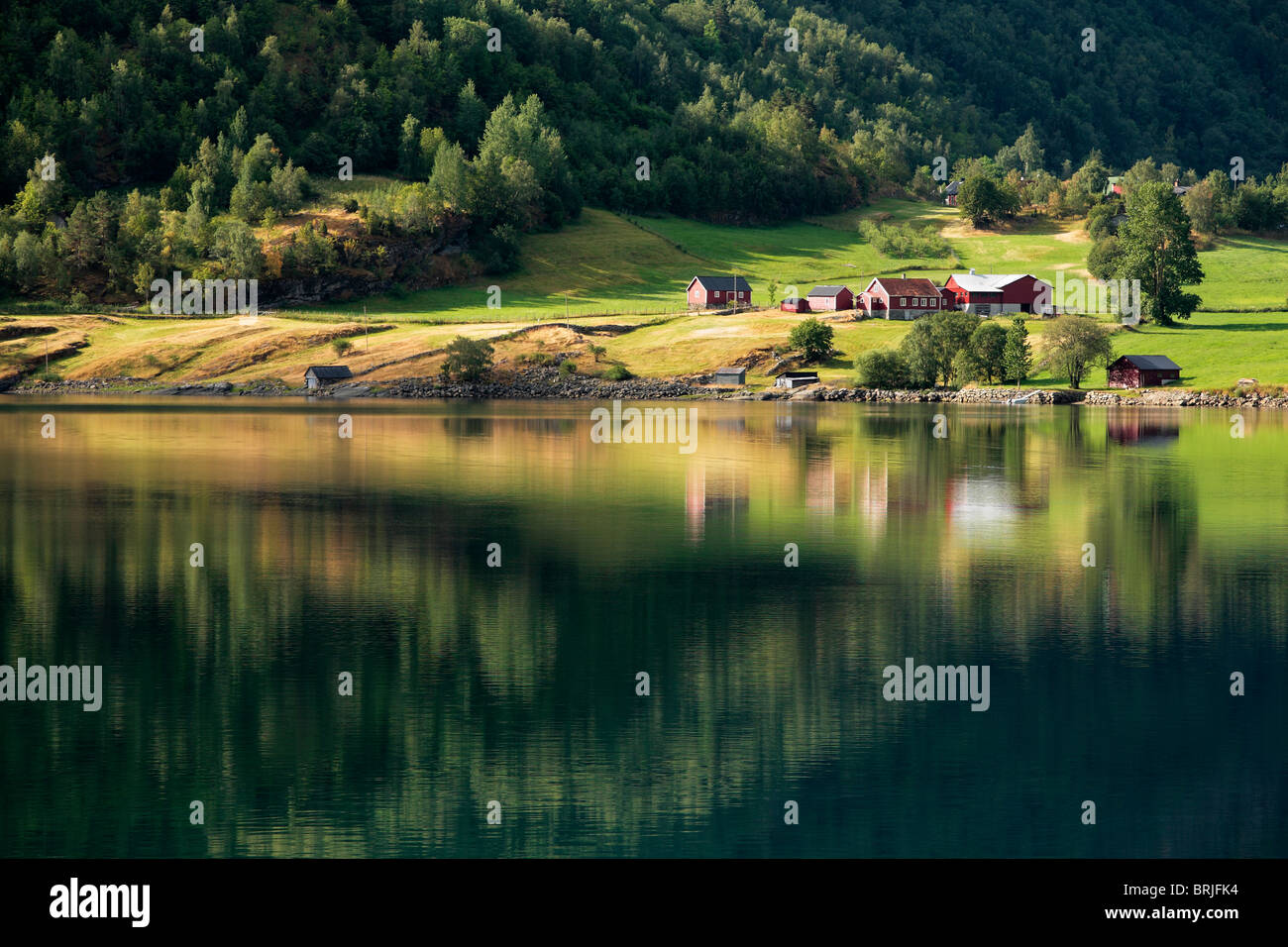 Un agriturismo è riflessa nelle acque vetroso di Sognefjord in Norvegia Foto Stock