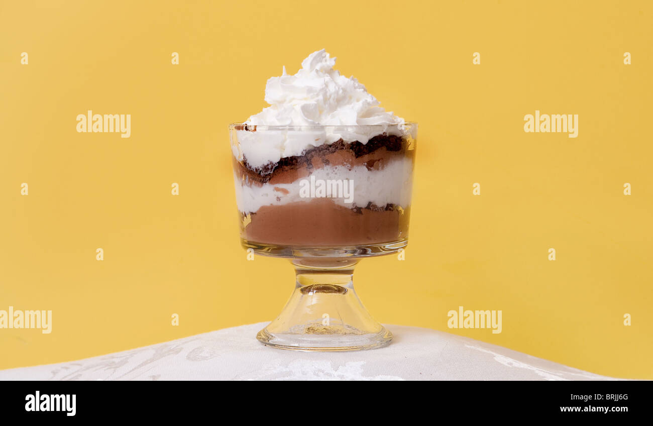 Mousse al cioccolato in un bicchiere dessert ciotola di fronte a un gradiente di sfondo giallo Foto Stock