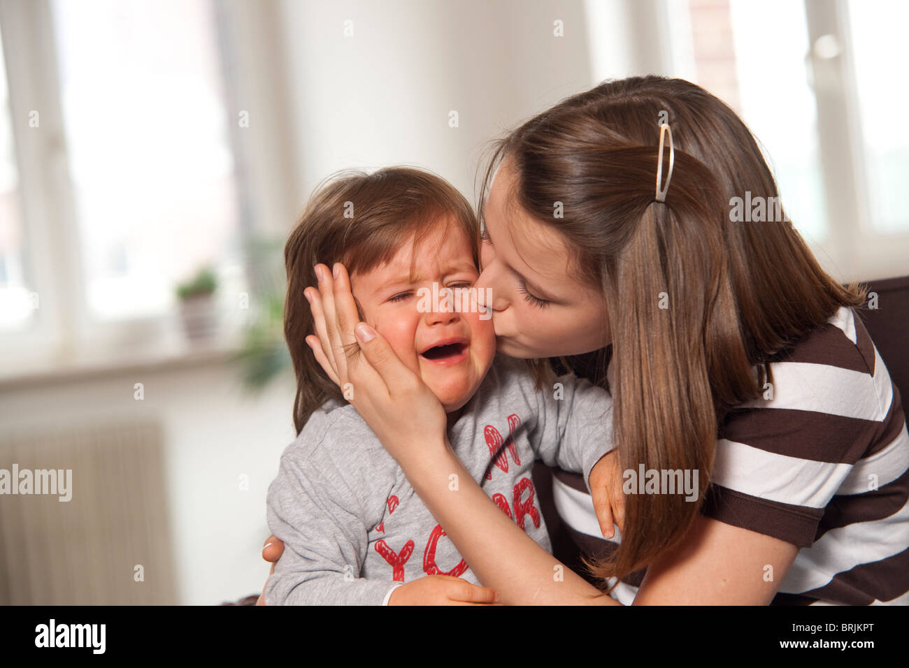 Ragazza baciare il pianto Baby Boy Foto Stock