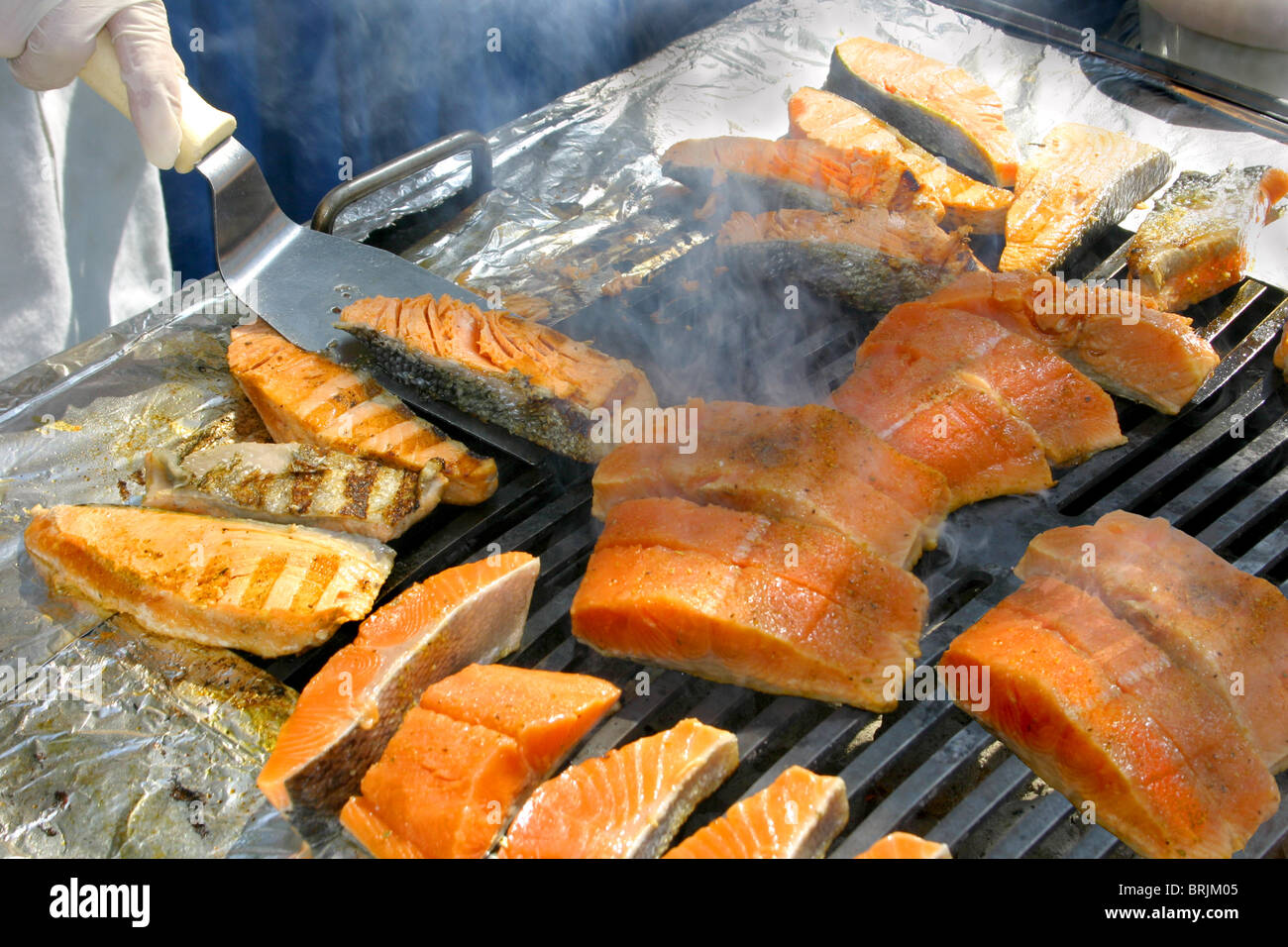 Un barbecue, una fiamma calda, e salmone essendo rivolta in fumo -- un weekend perfetto cookout o una vacanza su una lussuosa nave da crociera Foto Stock