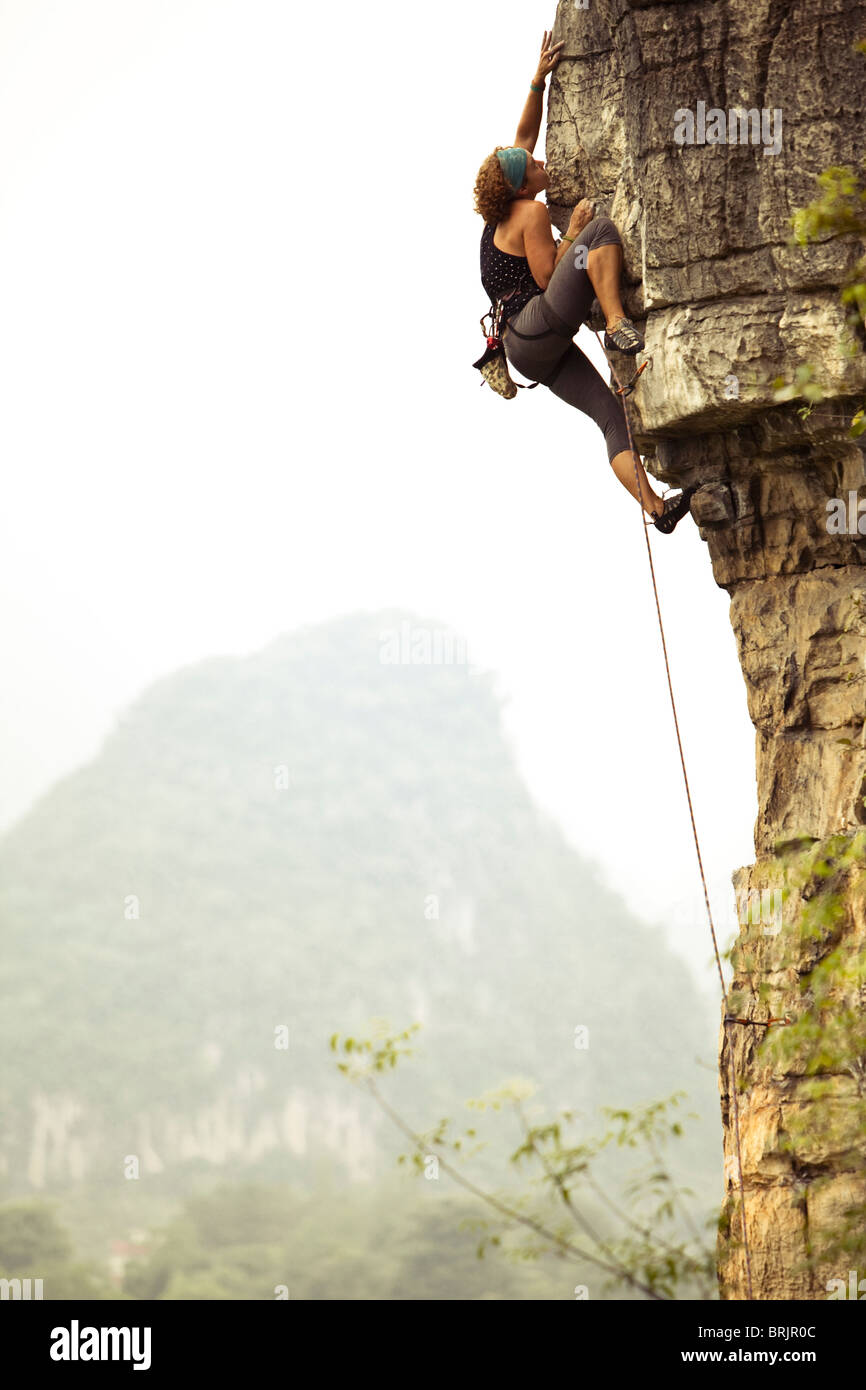 Scalatore femmina raggiungendo fuori per tenere distanti sul sovrastante il calcare in Cina. Foto Stock