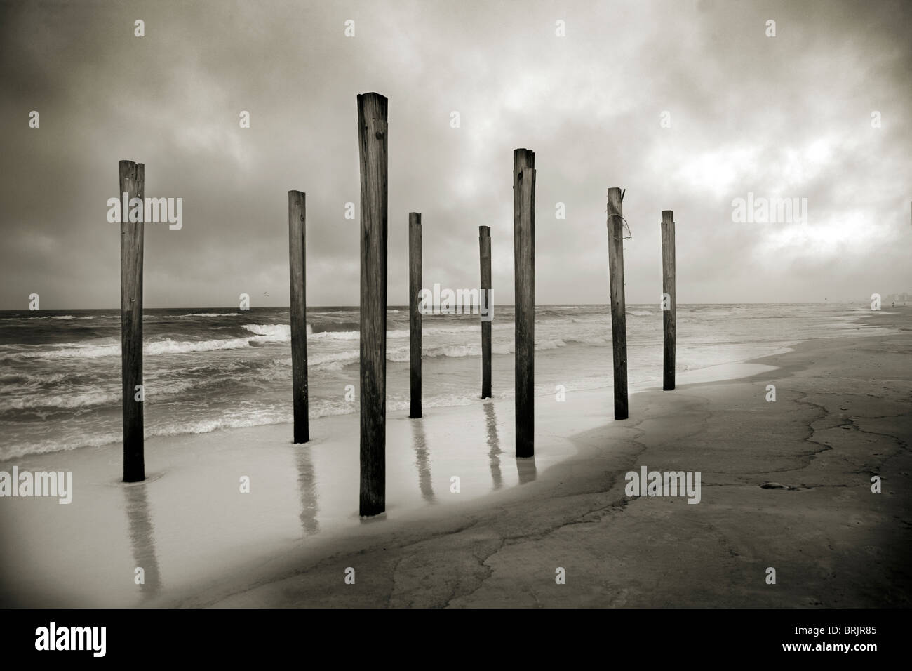 Una tonalità seppia shot della vecchia spiaggia posti presso il litorale con le nuvole e il mare in background. Foto Stock